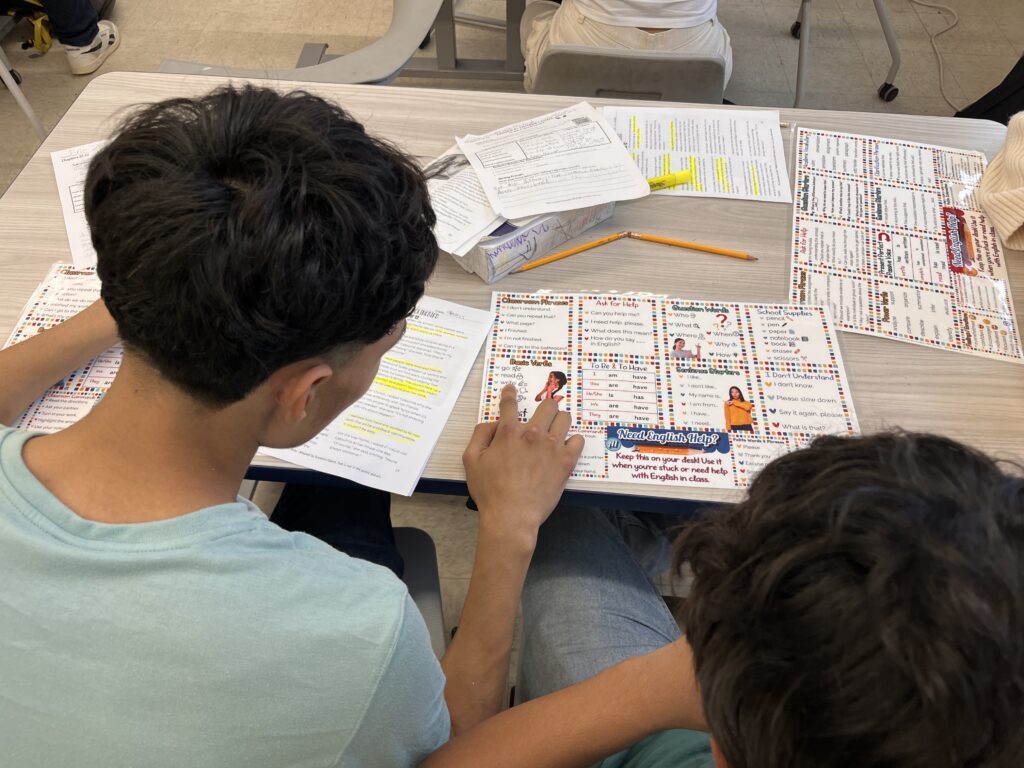 Two ESL teen students using laminated desk mats to support their reading and classroom participation