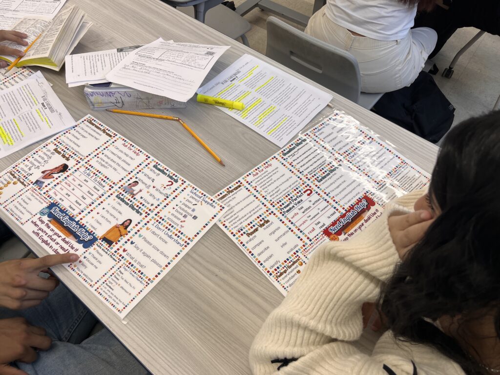 Two ESL students using laminated Survival English Desk Mats during a reading and writing activity at their desks.