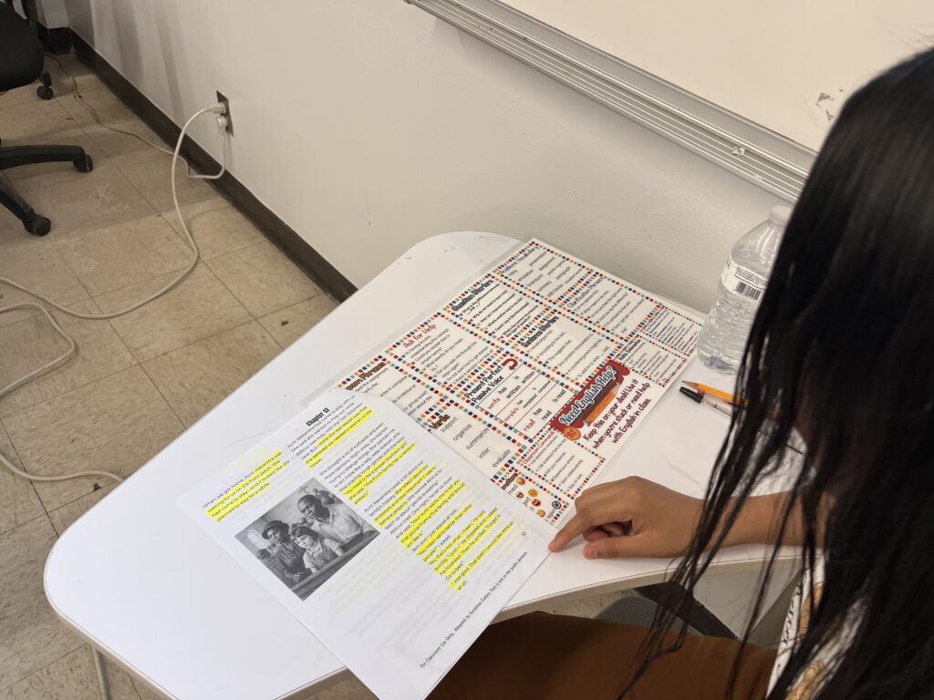 ESL student using a laminated desk mat to support reading comprehension during a summer school lesson
